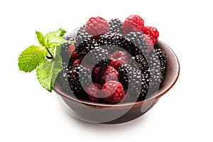 Raspberry, blackberry and mint leaf in ceramic brown bowl isolated on white