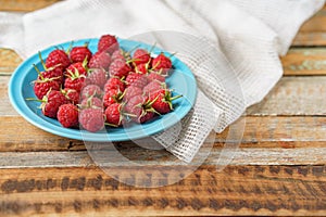 Raspberry in blue dish and in front of white fabric on old vi