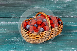 Raspberry with blueberry in basket on an old blue board