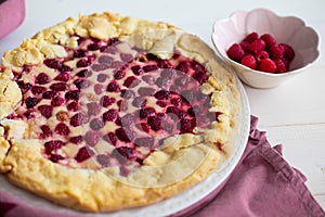 Raspberry cake or galette on white table, side view