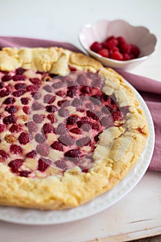 Raspberry cake or galette on white table, side view, vertical shot