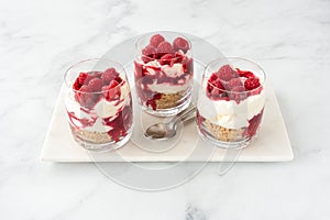 Raspberry Cheesecake Dessert in Three Glasses on White Marble Board