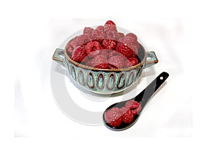 Raspberry in dish, berries in clay plate, dessert in bowl next to black ceramic spoon, isolated red fruit in cup