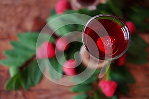 Raspberry fruit liqueur in two shot glasses with berries and green leaves