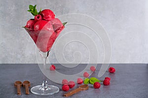 Raspberry ice cream sorbet in glass with chocolate spoon, raspberry, mint leaves copy space