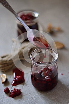 Raspberry jam dripping from a spoon on the table