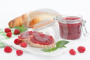 Raspberry jam with fresh raspberries and bread slices on white background