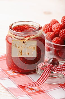 Raspberry jam in glass jar and raspberries.