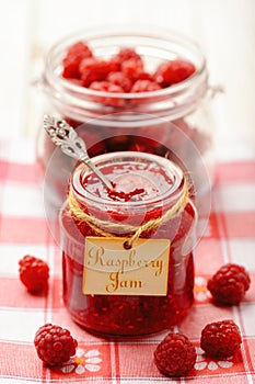 Raspberry jam in glass jar and raspberries. Selective focus.