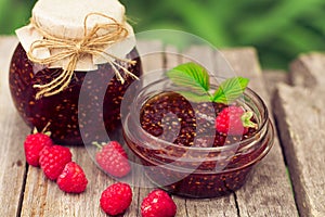 Raspberry jam in a jar and fresh berries on the wooden table