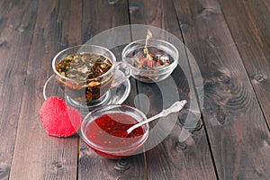 Raspberry jam on table with cup of herbal tea