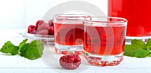 Raspberry liqueur in glass and fresh berries on a white background. Alcoholic flavored drink. Banner