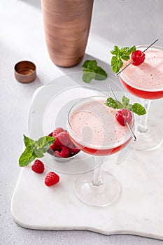 Raspberry martini in coupe glasses garnished with fresh raspberries and mint