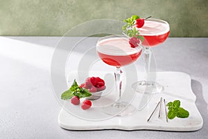 Raspberry martini in coupe glasses garnished with fresh raspberries and mint