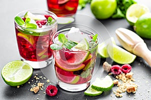 Raspberry mojito cocktail with lime, mint and ice, cold, iced refreshing drink or beverage closeup