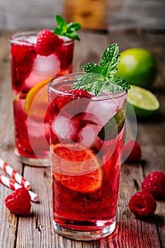 Raspberry Mojito Lemonade with lime and fresh mint in glass on wooden background