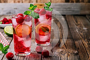 Raspberry Mojito Lemonade with lime and fresh mint in glass on wooden background