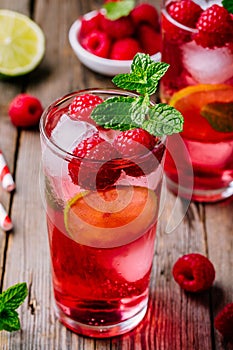 Raspberry Mojito Lemonade with lime and fresh mint in glass on wooden background