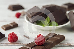 Raspberry, pieces of chocolate, chocolate shavings and mint on white Provence style table