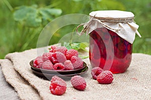 Raspberry preserve in glass jar and fresh raspberries