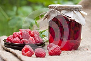 Raspberry preserve in glass jar and fresh raspberries