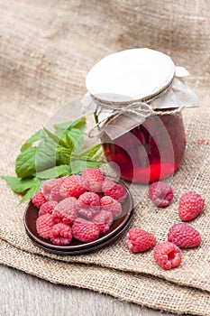 Raspberry preserve in glass jar and raspberries