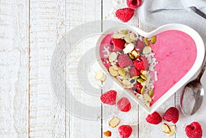 Raspberry smoothie in a heart bowl with superfoods, side border