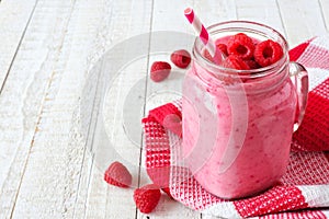 Raspberry smoothie in a mason jar against white wood, side orientation