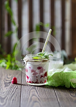 Raspberry smoothie, milkshake in a glass jar on a dark wooden background. Yogurt cocktail. Natural summer detox drink