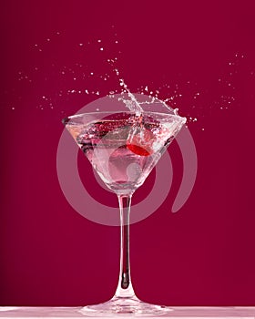 Raspberry splash in a martini cocktail glass on red background