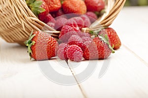 Raspberry and strawberries in a basket on the table in garden