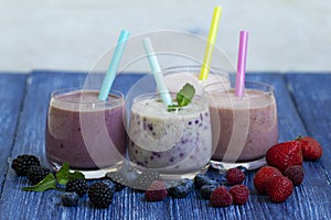 Raspberry, strawberry, blackberries, blueberry smoothie on blue wooden background. milkshake with fresh berries. healthy