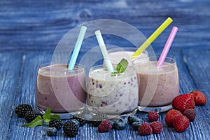 Raspberry, strawberry, blackberries, blueberry smoothie on blue wooden background. milkshake with fresh berries. healthy