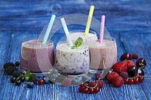 Raspberry, strawberry, blackberries, cherry smoothie on blue wooden background. milkshake with fresh berries. healthy