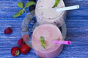 Raspberry, strawberry, blueberry smoothie on blue wooden background. milkshake with fresh berries. fruit smoothie with