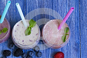 Raspberry, strawberry, blueberry smoothie on blue wooden background. milkshake with fresh berries. fruit smoothie with