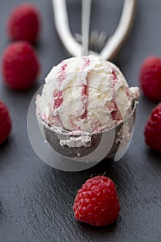 Raspberry-vanilla-icecream in icecream scoop, fresh raspberries on slate