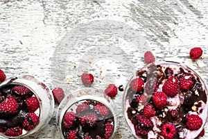 Raspberry yogurt dessert with fresh berries, chocolate and granola in glasses