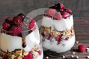 Raspberry yogurt parfait in glasses with chocolate, granola and chia seeds