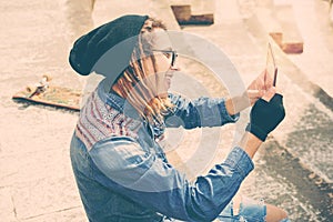 Rasta guy taking selfie sitting on a staircase with tablet warm