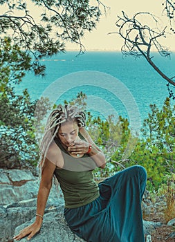 rastafarian girl with dreadlocks smoking on the mediterranean coast