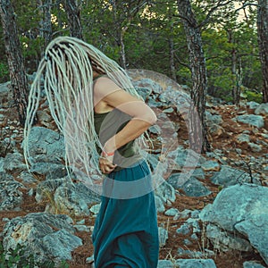 a rastafarian girl with dreadlocks walks on the rocks