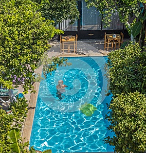 a Rastafarian girl swims in the hotel pool