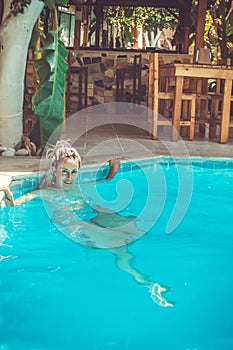 a Rastafarian girl swims in the hotel pool