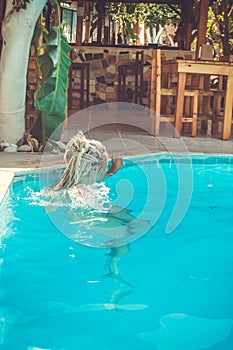 a Rastafarian girl swims in the hotel pool