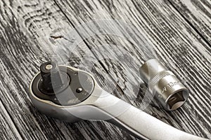 Ratchet wrench with replaceable nozzles on a black wooden table.