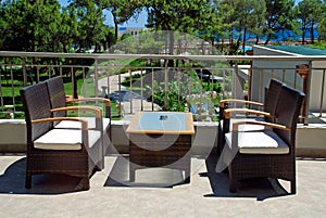 Rattan armchairs on resort terrace lounge .
