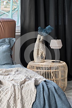 Rattan bedside table with decorative vase and lamp