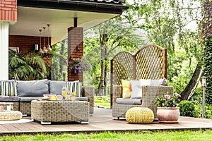 Rattan garden furniture with grey pillows, table with fruit on a