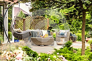 Rattan garden furniture and hanging chair on wooden terrace of h